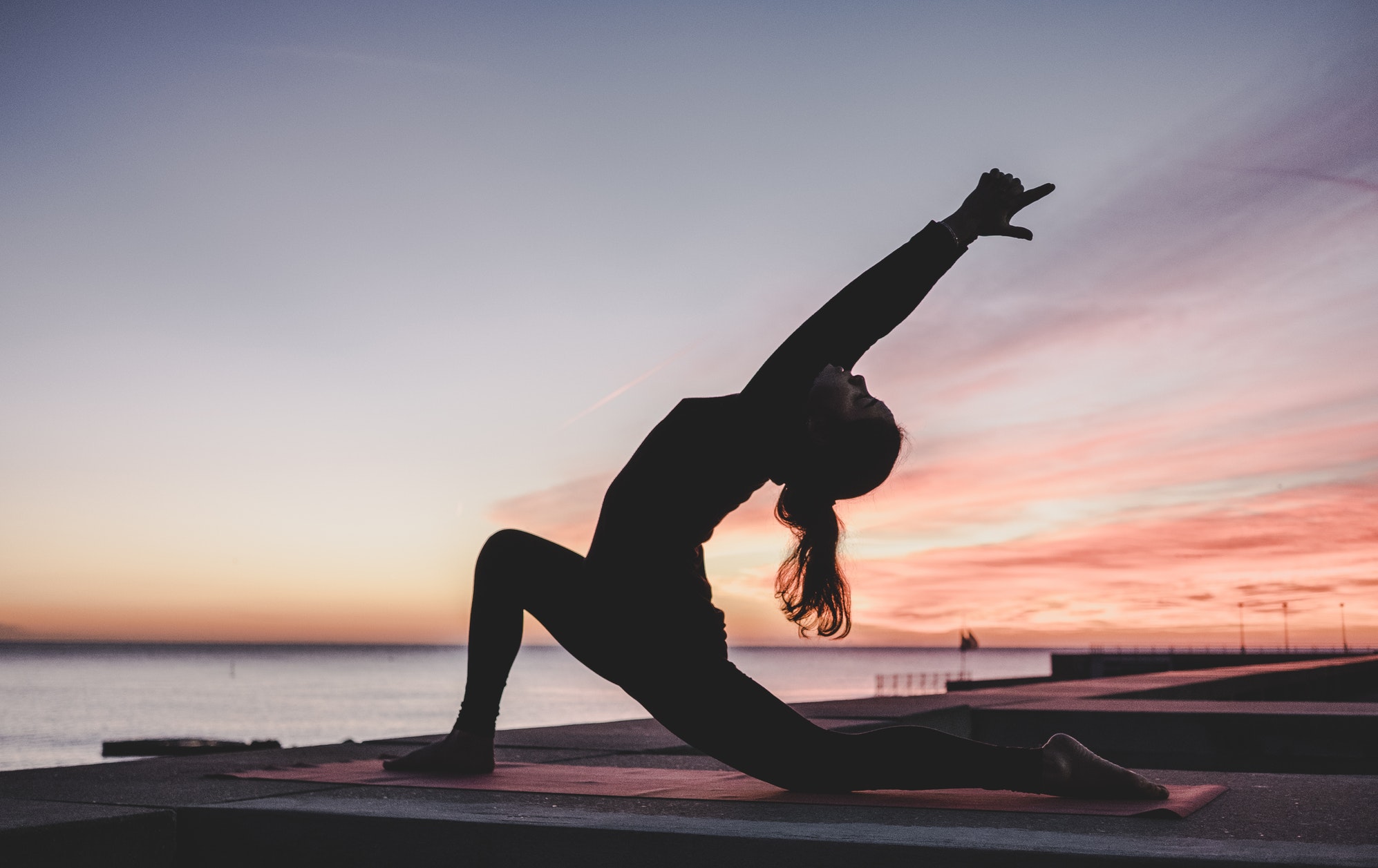 Woman doing yoga on a pier.